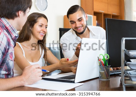 Smiling colleagues watching something using laptop in the office