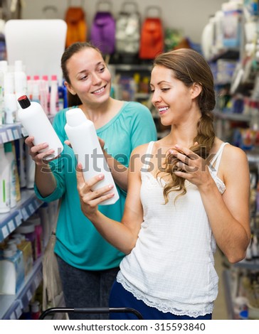 Adult woman in good spirits selecting a shampoo at store