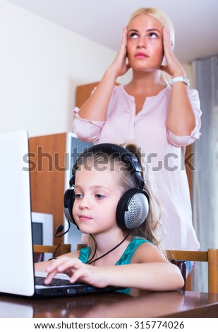 Frustrated blonde woman catching her little daughter watching forbidden site online