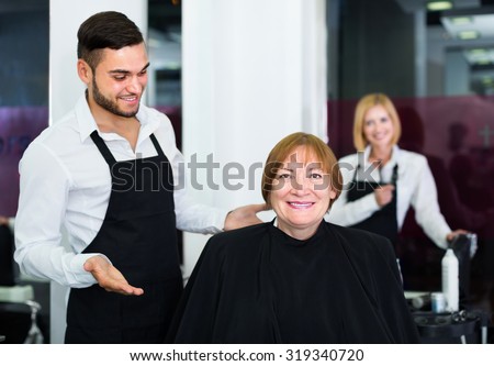 Mature woman contented haircut at the hair salon with barber and smiling