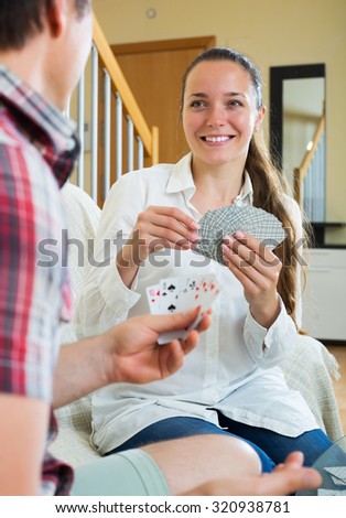 Relaxed young couple communicate while playing cards sitting on the sofa