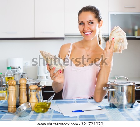 Happy young woman sitting at the table with money