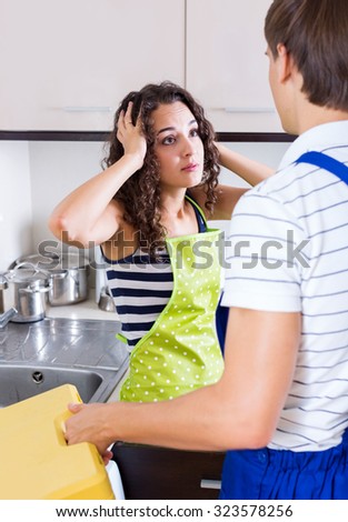 Unhappy young woman shocked of smatter plumber coming to help