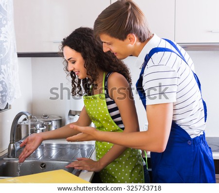 Satisfied adult woman client thanking professional plumber for work