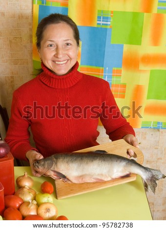 Mature woman with red fish in her kitchen