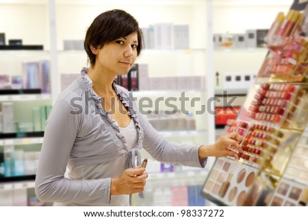 young woman chooses the lipstick at cosmetics  shop