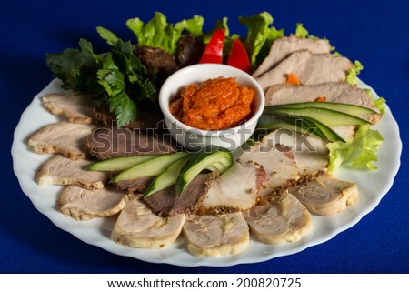 Meat with greens, cucumbers and squash caviar isolated on blue