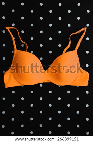 Orange bra on black and white polka dot background