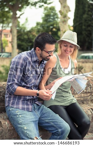 Two tourists stand together looking at a map, trying to figure out where they are, or where they want to go.