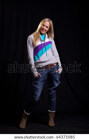 Informal blonde in casual clothing posing on the black backdrop