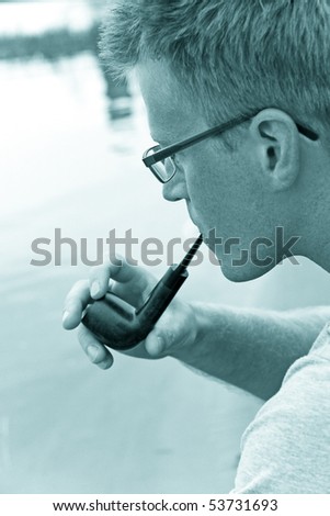 man smoking a pipe, river on background