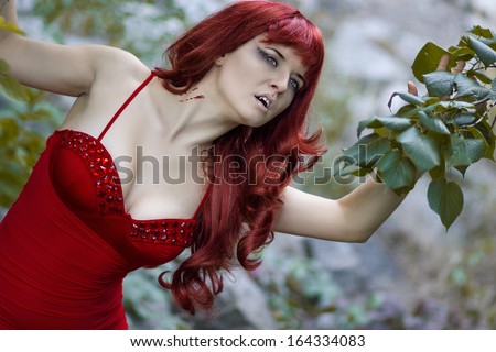 Portrait of a beautiful young woman in a long red wig with gothic makeup in the form of a vampire for Halloween
