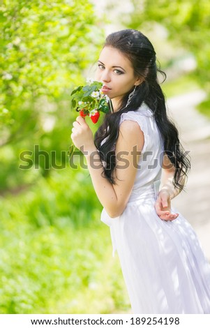 Beautiful young brunette posing in nature. Girl with hair and makeup in white romantic dress
