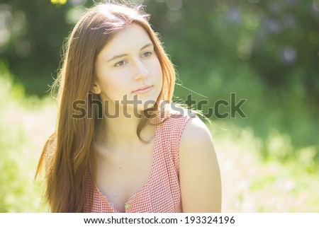 Portrait of a beautiful young woman with brown hair in retro plaid dress. Girl posing in nature with a small bouquet of violets