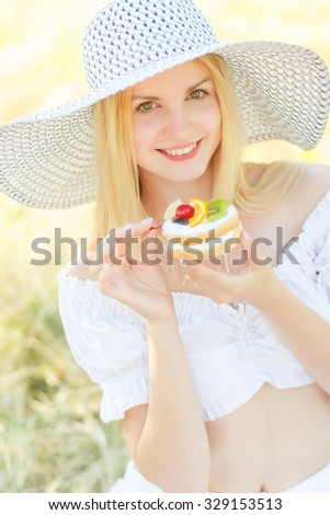 Young pretty blonde fashion girl sensual portrait posing outdoor in summer eating cake with fruits. Soft focus