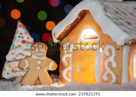 Gingerbread house with gingerbread man and christmas trees. Gingerbread man cookie behind the door. Christmas decoration.
