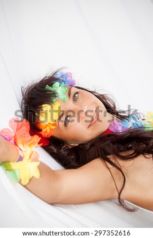 Portrait of relaxed pretty young woman with accessories in Hawaii style lying in white hammock