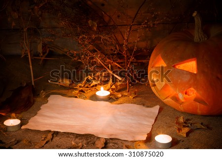Scary Halloween pumpkin and old burned paper ad layout with candlelight and autumn leafs. Still life. Wooden background.