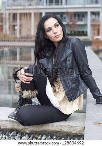 woman sitting on fountain fence, knee up