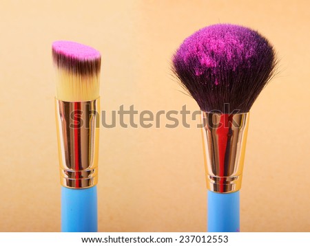 Makeup brush and cosmetic blush. On a beige background