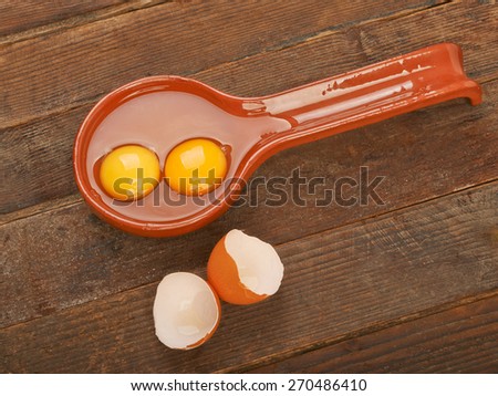 Raw eggs in a clay spoon on wooden table