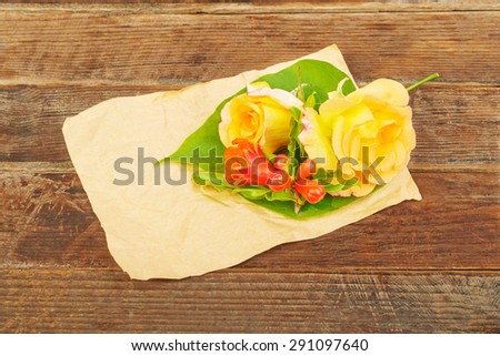 Flowers yellow roses leaves and flowers of pomegranate on a wooden background