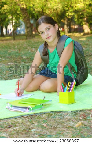 beautiful girl sitting on a blanket in the park and learn, soft focus, best focus on the face girls