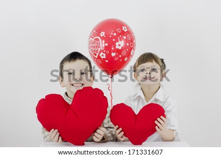 boy and girl hold heart in hands and smile,best focus glasses, teeth, boy, soft focus hand and a balloon