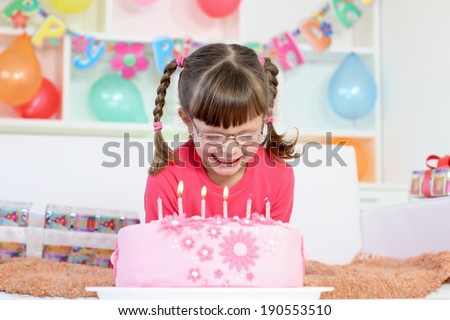 girl with glasses blows out the candles on the cake
