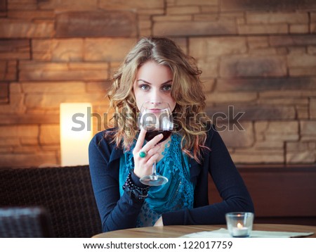 Beautiful Girl In Restaurant holding glass with red wine. European Beautiful Girl. Girl In Restaurant. European Beauty,