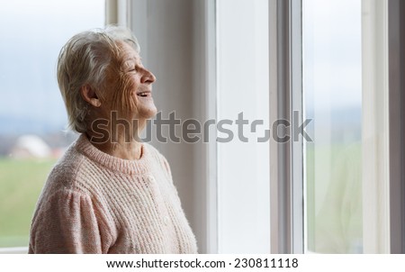 Portrait of Elderly woman looking out window, Grandmother smiling