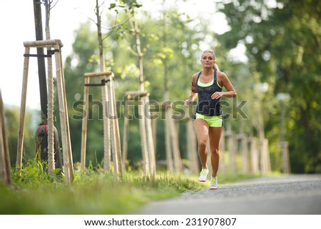 Young lady running. Woman runner running through the spring park road. Workout in a Park. Beautiful fit Girl. Fitness model outdoors. Weight Loss
