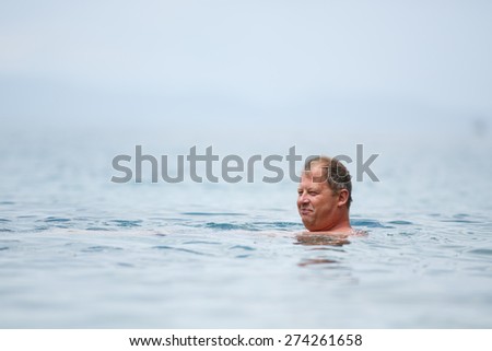 Handsome old man swimming in the sea during summer in Croatia