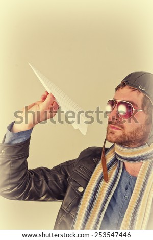 Aviator pilot with hat and sunglasses plays with paper planes
