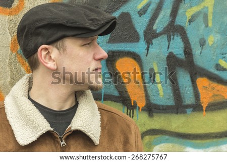 Cool guy rocks an aviator jacket and newsboy cap as he takes a moment to think
