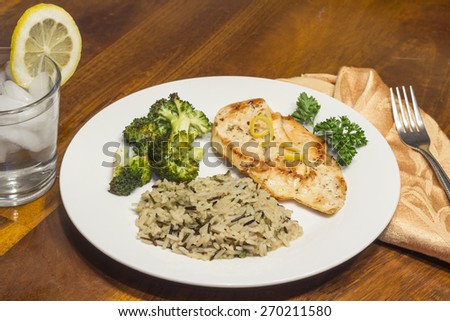 Crispy tender lemon chicken garnished with lemon twist with sides of herb wild rice and lemon broccoli