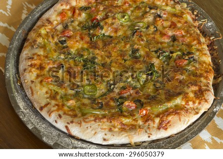 Home made artisan veggie pizza pie with onions peppers spinach and olives