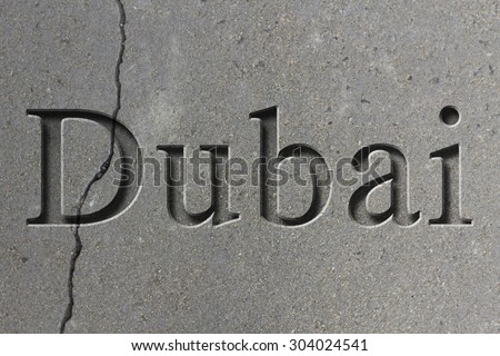 Engraving spelling the city Dubai on textured old surface