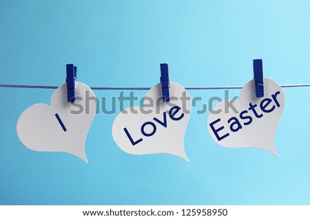 I Love Easter message written across 3 heart tags hanging from line against a blue background.