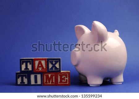 Pink piggy bank with Tax Time message on building blocks for Tax Day or End of Financial Year financial returns or retail stock-take sales.