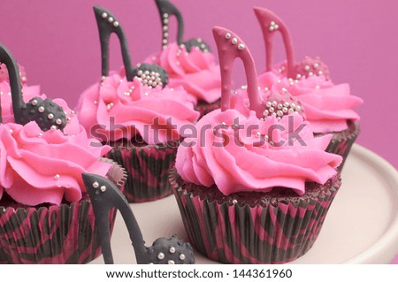 Female high heel shoes decorated pink and black red velvet cupcakes with high heel shoes for teenage, female birthday, or wedding bridal shower - close up.