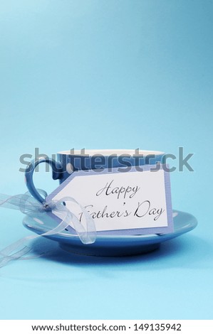 Happy Fathers Day gift tag with a cup of coffee or tea for Dad in a blue polka dot cup and saucer against a blue background. Vertical with copy space for your text here.