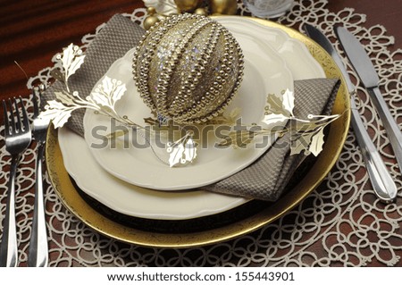 Latest trend of gold metallic theme Christmas  formal dinner table place setting with fine bone china, bauble and festive decorations. Close up.