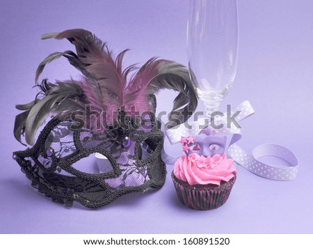 Pink and purple masquerade masks decorated party cupcake with pink frosting for teenage, birthday, New Years Eve, or wedding bridal shower party, with mask and champagne glass.