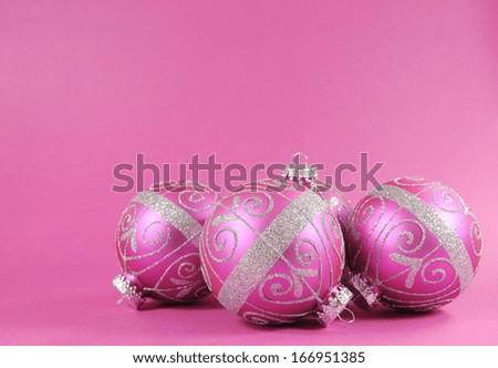 Beautiful fuchsia pink festive bauble ornaments on a feminine pink background with copy space for Merry Christmas or Happy Holidays seasons greetings.