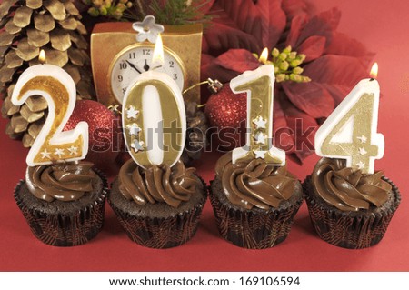 Happy New Year chocolate cupcakes with 2014 number candles against red festive background.