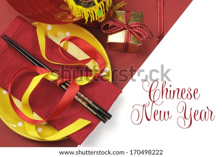 Happy Chinese New Year dining table place setting with red and gold decorations and chopsticks with greeting message text.