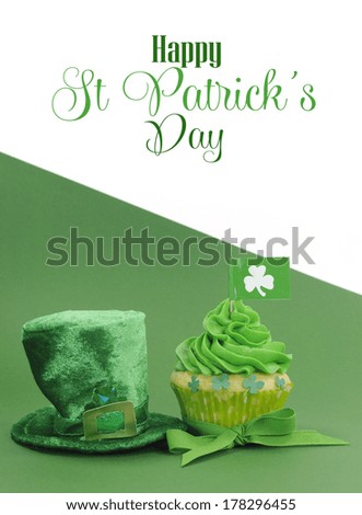 Happy St Patrick\'s Day green cupcakes with shamrock flags and leprechaun hat against a green background