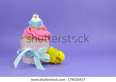 Happy Easter pink, yellow and blue cupcakes with cute chicken decorations on purple background for children party or holiday treat, with copy space.