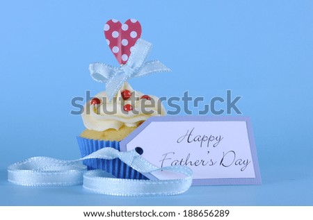 Happy Fathers DAy cupcake with red and white decorations with heart topper on pale blue background.